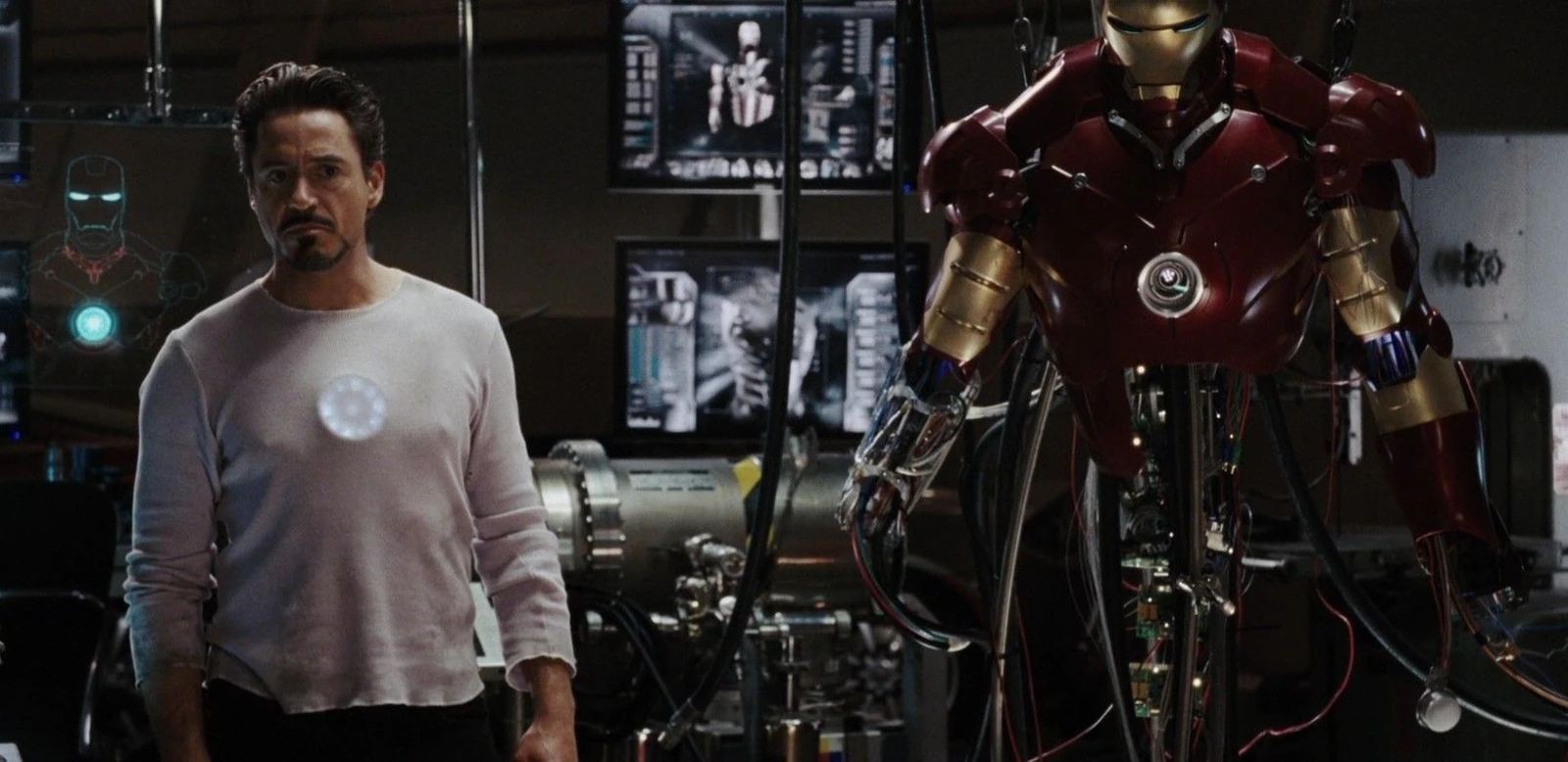 Tony Stark beside an Iron Man suit in his workshop